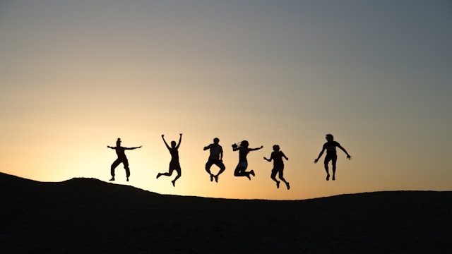 Silhouette von springenden Menschen im Sonnenuntergang