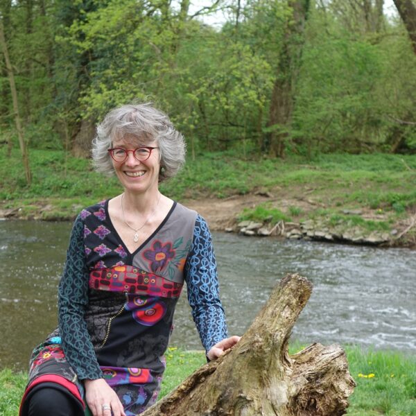 Eva Huneck auf Baumstumpf am Fluss